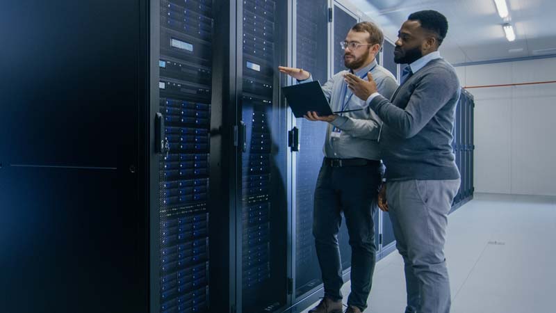 Two IT professionals working in a server room