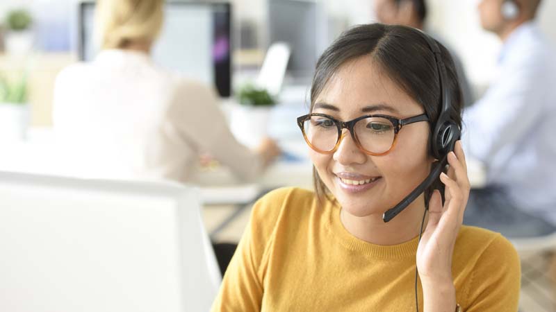 Asian professional working at computer with headset on